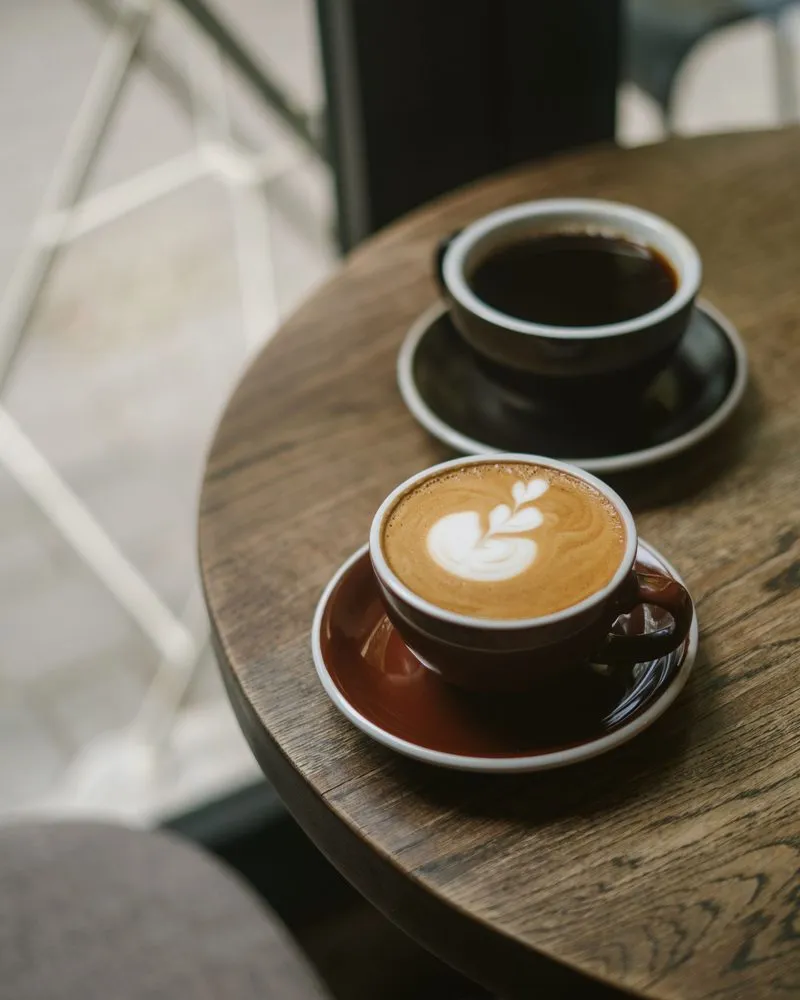 Two cups of coffee on a small round wooden table
