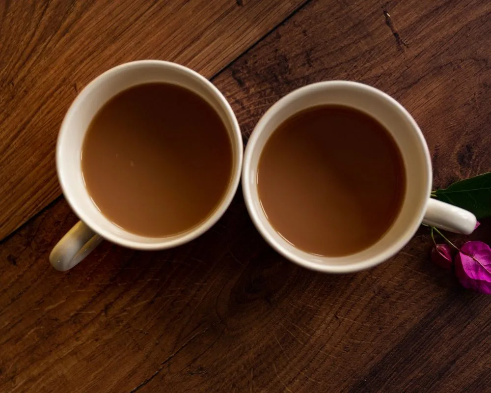 Two mugs of coffee with milk on a dark wooden table