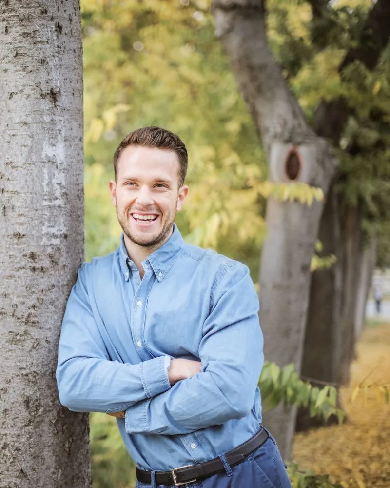 Pastor James Holloway leaning against a tree, arms crossed, smiling