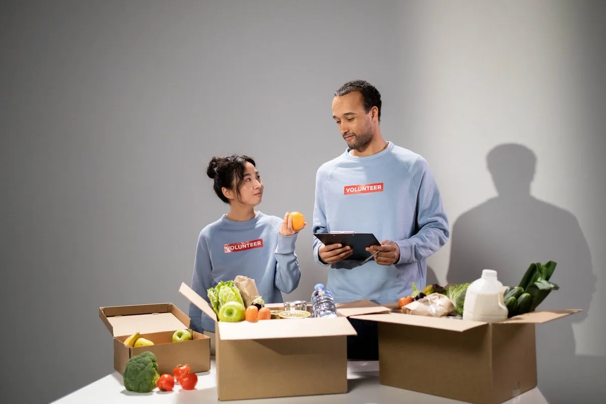 Two volunteers packing boxes of fresh vegetables and groceries